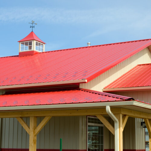 Red metal roofed building with weather vain.